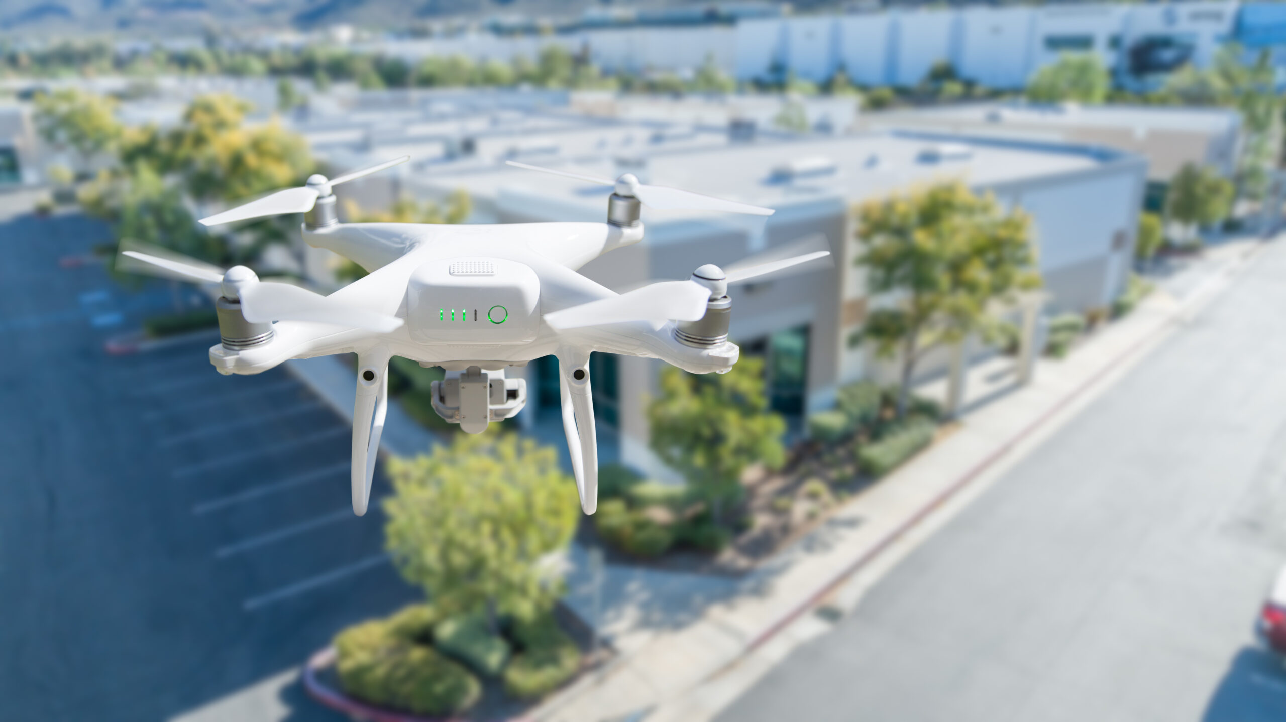 Unmanned Aircraft System Quadcopter Drone In The Air Near Corporate Industrial Building.